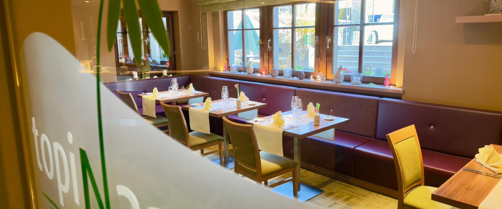 Restaurant Topinambur im Hotel in Rothenburg ob der Tauber mit gedeckten Tischen und Sitzbänken am Fenster