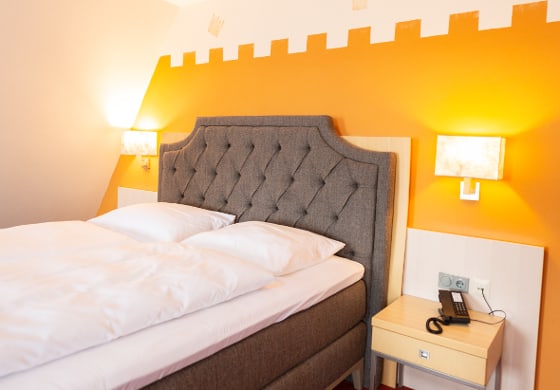 Modernes Doppelzimmer mit gepolstertem Kopfteil, Nachttischen und Beleuchtung im Prinzhotel Rothenburg ob der Tauber
