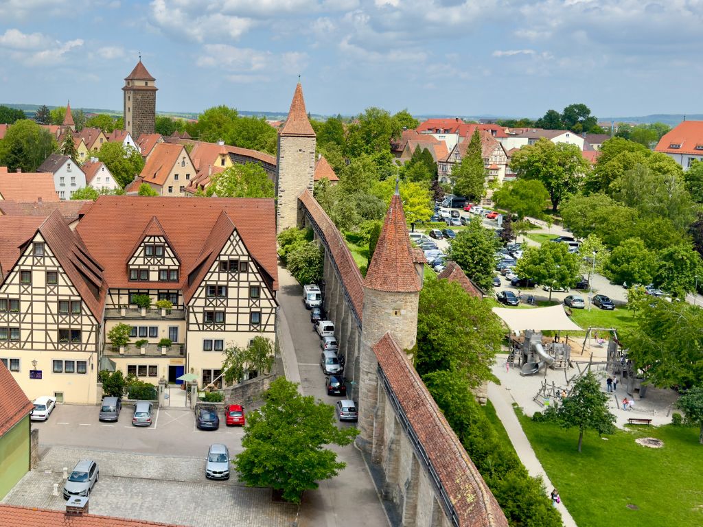 Luftaufnahme von Rothenburg ob der Tauber: Fachwerkhäuser, mittelalterliche Stadtmauer, Spielplatz und grüne Umgebung.