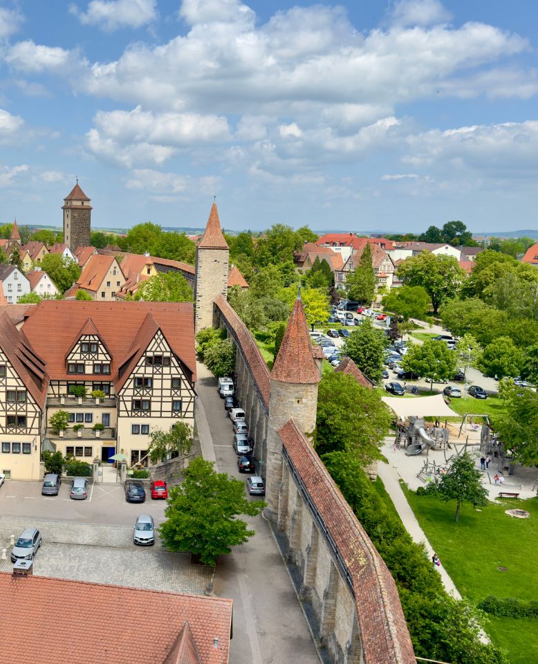 Luftaufnahme von Rothenburg ob der Tauber: Fachwerkhäuser, mittelalterliche Stadtmauer, Spielplatz und grüne Umgebung.