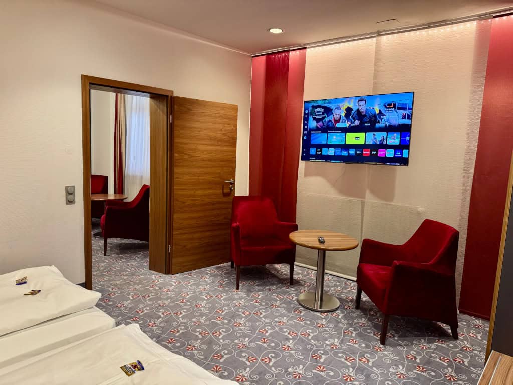 Gemütliche Sitzecke mit roten Sesseln und Fernseher im Familienzimmer des Prinzhotel Rothenburg