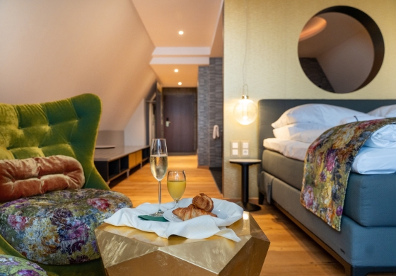 Aqua Spa Suite im Prinzhotel Rothenburg &ndash; modernes Doppelbett mit Sitzbereich und Fr&uuml;hst&uuml;ck auf dem Tisch