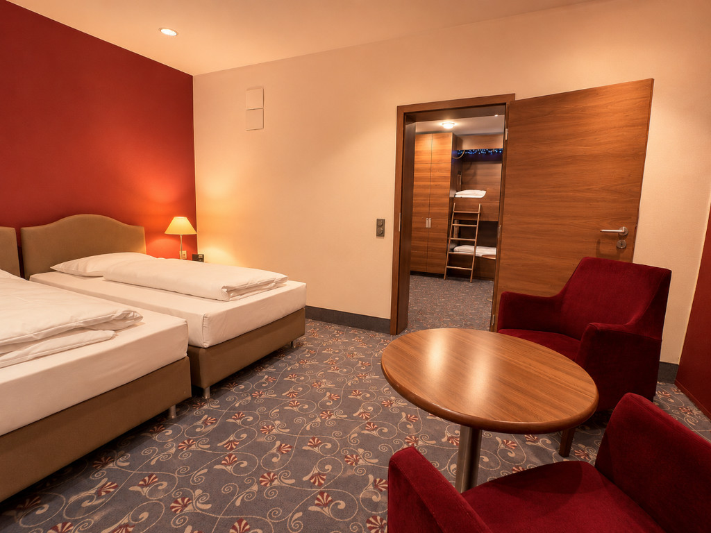 Blick in ein Hotel-Familienzimmer mit zwei Einzelbetten im Vordergrund und einem angrenzenden, durch eine offene Tür sichtbaren Kinderschlafbereich mit Etagenbett.